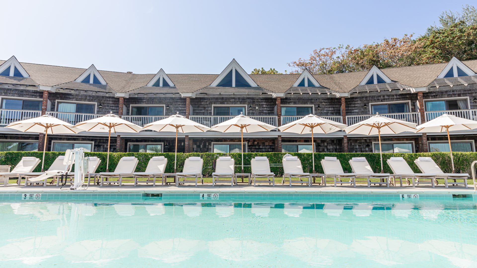 A Pool With Chairs And Umbrellas By A Building