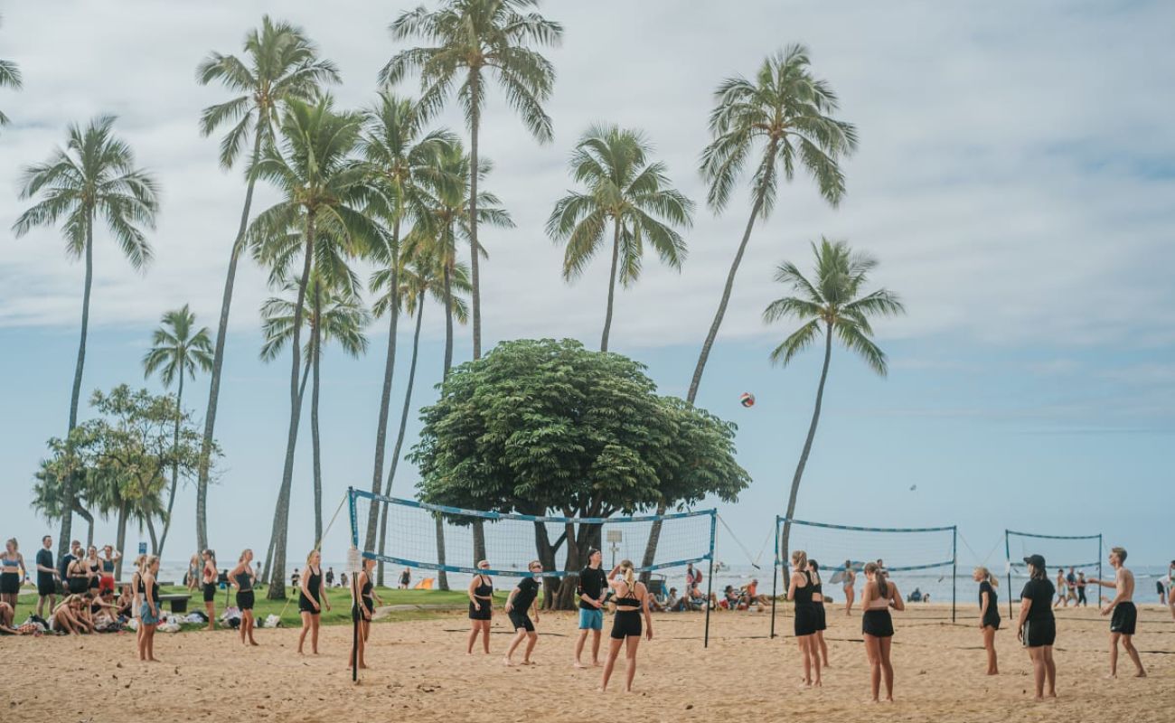 A Group Of People Playing Volleyball On A Beach
