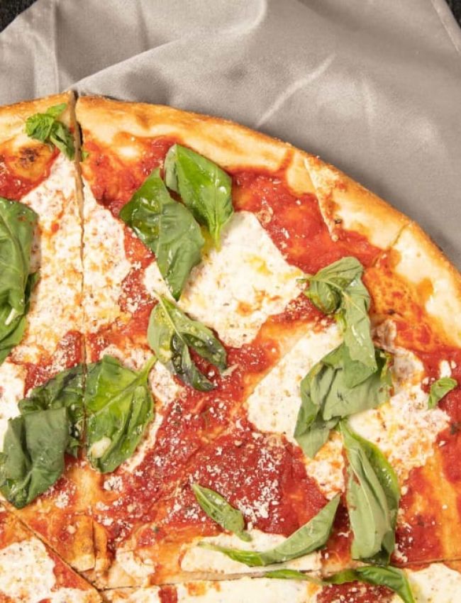 A Pizza With Basil On It