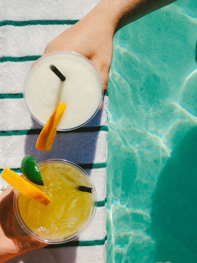 A Person's Foot In A Pool With A White Ball And A Lemon Slice On The Edge