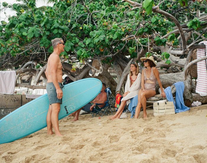 A Group Of People Stand Around A Surfboard