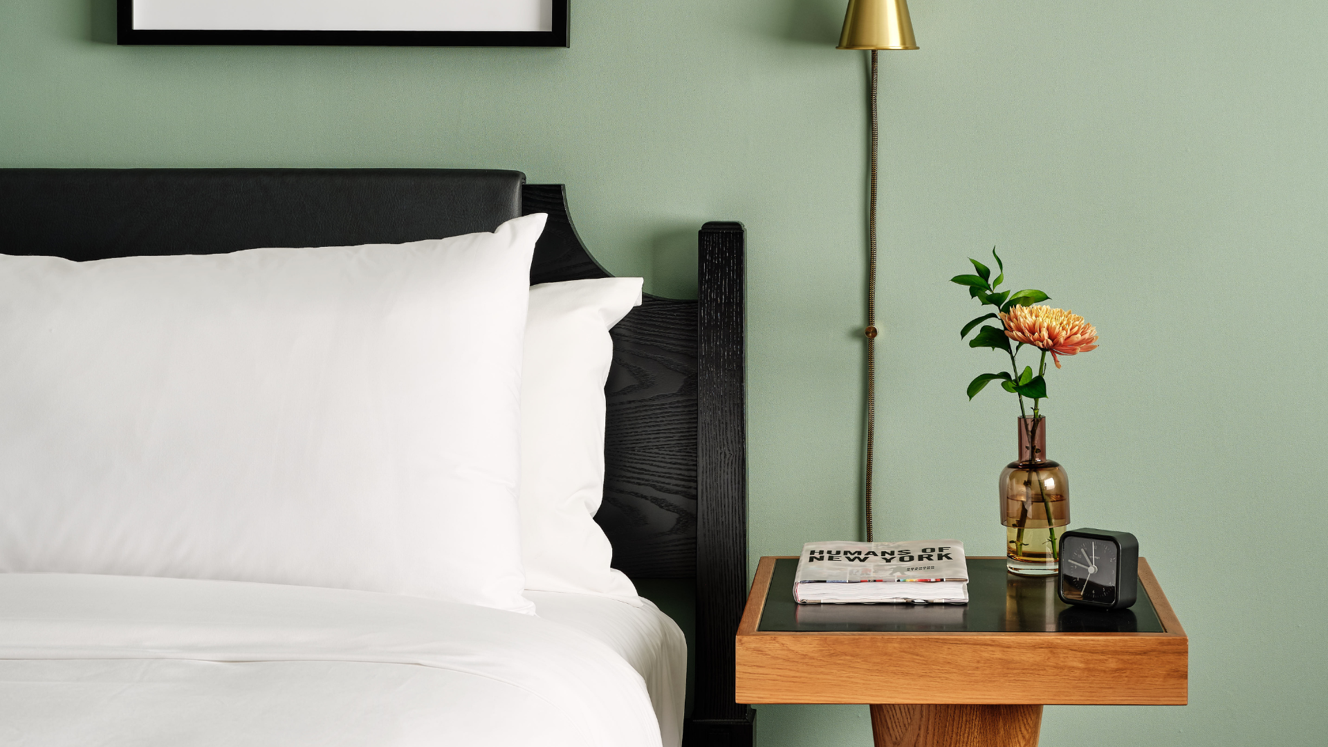 A Bed With A Lamp And A Vase With Flowers On It