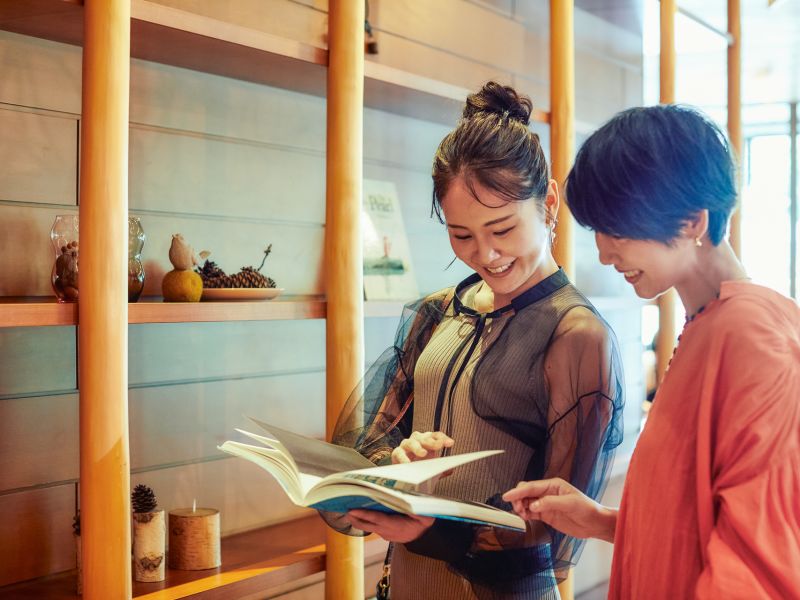 A Person Showing A Person Something On A Book