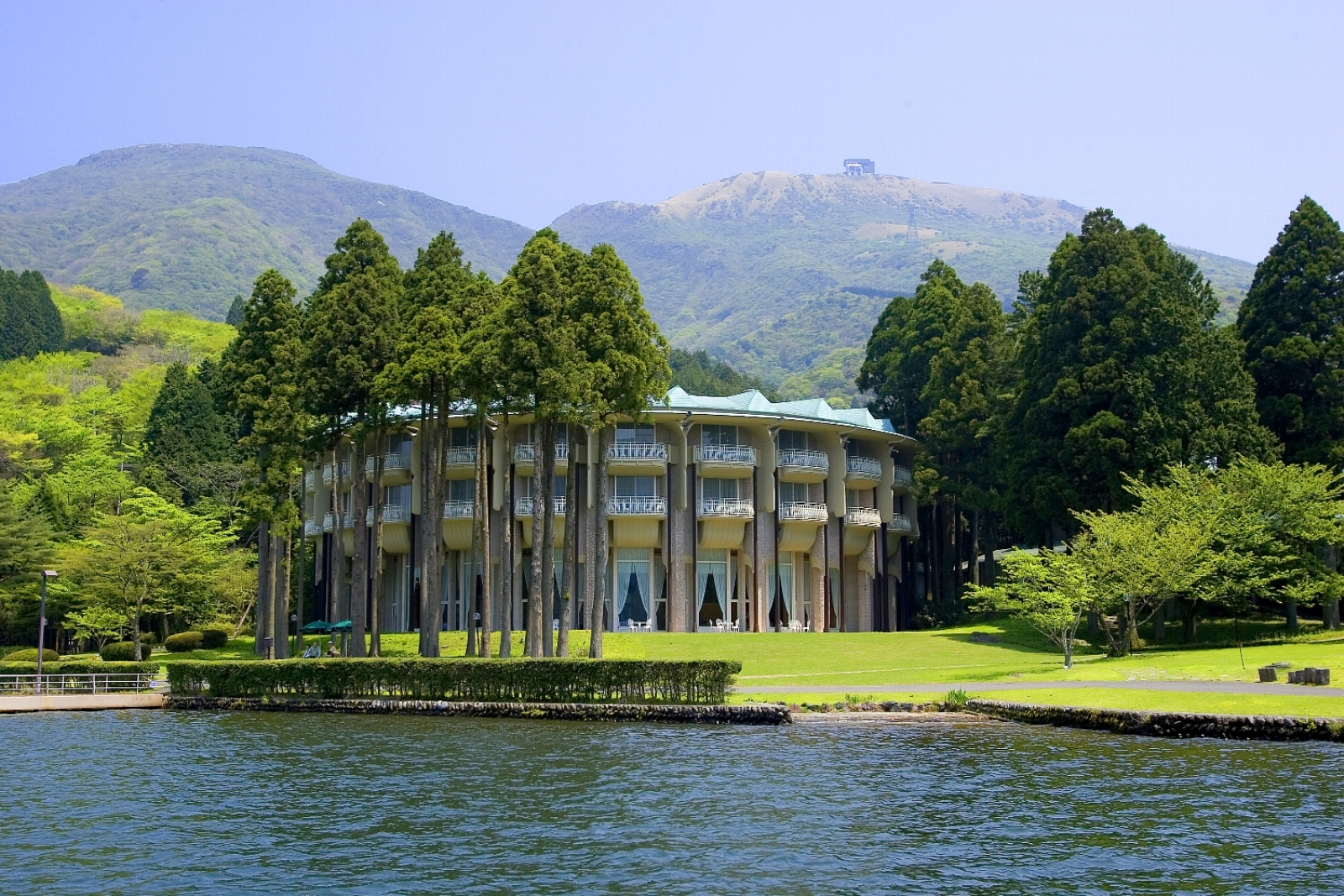 A Building With A Lake In Front Of It And Trees Around It
