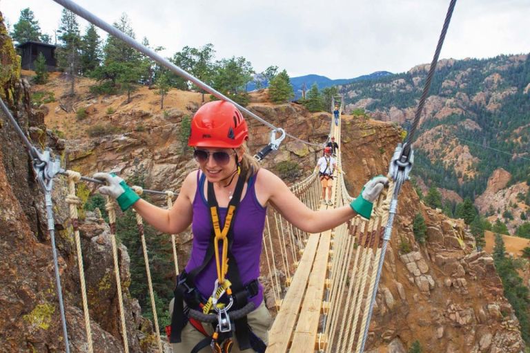 A Person Wearing A Helmet And Climbing A Rope Bridge