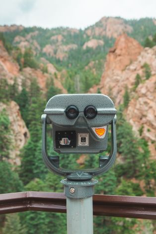 A Black And Silver Camera On A Metal Pole With A Rocky Mountain In The Background