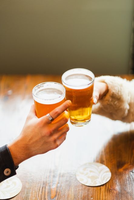 A Couple Of Hands Holding Glasses Of Beer