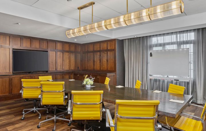 A Room With Yellow Chairs And A Large Screen