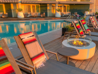 A Pool With Chairs And A Table With A Fire In It
