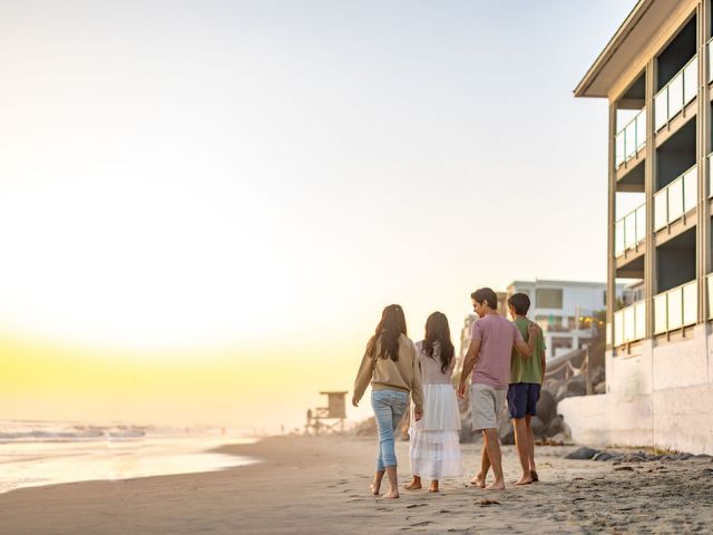 A Group Of People Walking On A Beach